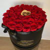 Red roses in a black round box with a gold rose at center