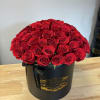 Red roses arranged in a black round box with a ribbon