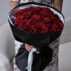 Bouquet of red roses wrapped in black paper with a white ribbon