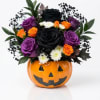 Halloween bouquet in a jack-o'-lantern vase with black, purple, and orange roses