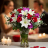 Bouquet of red roses, white lilies, and purple orchids in a glass vase