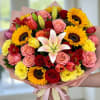 Bouquet of sunflowers, roses, tulips, and a white lily in pink wrap