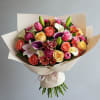 Bouquet of mixed roses, lilies, calla lilies, and pink blooms wrapped in beige paper