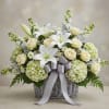 White lilies and cream roses in a wicker basket with a silver ribbon