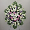 Standing floral spray with white lilies, roses, and purple accents
