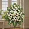 White floral standing spray with roses and lilies on an easel