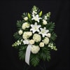 White lilies and roses in a standing spray with a white ribbon