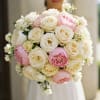 Round bouquet of white and pink roses held in front of a dress