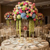 Tall floral centerpiece with pink roses and blue hydrangeas in a clear vase