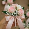 Pink rose boutonniere with white filler flowers and a satin ribbon
