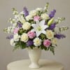 White lilies, roses, carnations, and purple flowers in a white vase