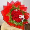 Red rose bouquet with green fern accents and a small teddy bear