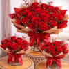 Three red rose bouquets wrapped in kraft paper with red ribbons