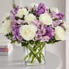 Bouquet of white roses and purple flowers in a clear glass vase