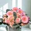 Pink roses and gerbera daisies in a white vase with a ribbon bow