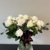 White rose bouquet in a clear glass vase with a burgundy ribbon