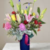 Colorful bouquet of lilies, tulips, and carnations in a blue vase