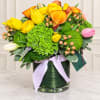 Bright bouquet of yellow and orange tulips with green blooms in a glass vase