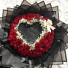 Heart-shaped bouquet of red roses with white baby's breath and a cream ribbon