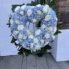Heart-shaped blue and white floral wreath on a stand
