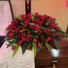 Large red rose funeral spray on a casket with a memorial ribbon