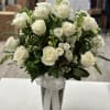 White rose bouquet in a clear glass vase with a white ribbon