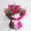 Bouquet of red roses with purple filler flowers wrapped in pink paper