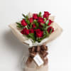 Bouquet of red roses wrapped in beige paper with a brown ribbon