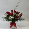 Red roses arranged in a glass vase with baby's breath and a red bow