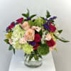 Mixed bouquet of roses, hydrangeas, and carnations in a glass vase