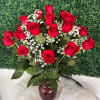 Red roses with white baby's breath in a red glass vase