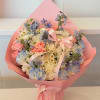 Bouquet of pink roses, white daisies, and blue flowers wrapped in pink paper