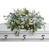 White and blue floral casket spray on a silver casket