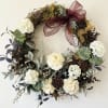 Floral wreath with cream blooms and a burgundy ribbon bow