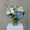 White roses and blue hydrangeas arranged in a clear glass vase