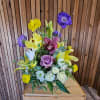 Mixed bouquet with purple, yellow, white, and pink flowers in a box