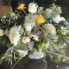 A fresh garden-style centerpiece featuring soft white blooms accented with seasonal greenery