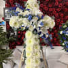 Large white floral cross on an easel with blue accents