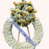 White floral funeral wreath with yellow roses and a ribbon on an easel