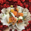 Bouquet of orange, white, and cream flowers wrapped in beige paper