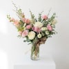 Pink and white flower arrangement in a glass vase with a burlap bow