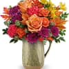 Mixed bouquet of orange, pink, and purple flowers in a metal pitcher