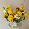 A bright and elegant arrangement featuring vibrant yellow roses, orchids, seasonal blooms