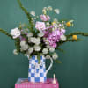 Mixed bouquet of pink and white flowers in a blue-and-white checkered pitcher