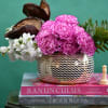 Pink carnations and white flowers in a patterned vase with greenery