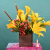 Yellow calla lilies and pink berries in a wooden box vase