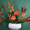Tropical floral arrangement in a white vase with red anthuriums and bird of paradise