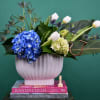 Blue hydrangea and white tulips in a white vase with spiky thistle accents