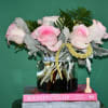 Pink and white roses in a glass vase with greenery