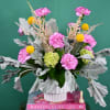 Pink carnations and yellow billy balls in a white vase